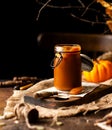 Homemade sweet and tasty pumpkin caramel n glass jar stands on wooden board