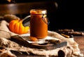 Homemade sweet and tasty pumpkin caramel n glass jar stands on wooden board