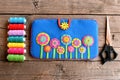 Homemade tablet cover. Felt blue case with bright flowers, thread set, scissors on old wooden background Royalty Free Stock Photo