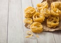 Homemade tagliatelle pasta in brown paper on white background