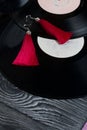 Homemade tassel earrings in red. Against the background of old vinyl records and brushed pine boards painted in black and white Royalty Free Stock Photo