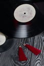 Homemade tassel earrings in red. Against the background of old vinyl records and brushed pine boards painted in black and white Royalty Free Stock Photo