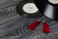 Homemade tassel earrings in red. Against the background of old vinyl records and brushed pine boards painted in black and white Royalty Free Stock Photo