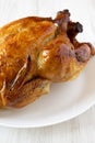 Homemade tasty rotisserie chicken on a white plate on a white wooden background, low angle view. Close-up Royalty Free Stock Photo