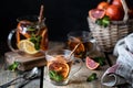 Homemade tea in a transparent glass with red orange and lemon, cinnamon and mint on a wooden background. Oranges Wicker Basket