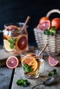 Homemade tea in a transparent glass with red orange and lemon, cinnamon and mint on a wooden background. Oranges Wicker Basket