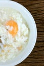 Homemade Thai Rice Soup With chicken, pork and Soft boiled egg or onsen egg in white blow on rustic wooden background. Thai style