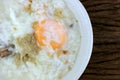 Homemade Thai Rice Soup With chicken, pork and Soft boiled egg or onsen egg in white blow on rustic wooden background. Thai style