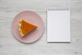 Homemade Thanksgiving pumpkin pie on a pink plate, blank notepad on a white wooden background, top view. Overhead, from above, Royalty Free Stock Photo