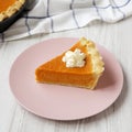 Homemade Thanksgiving pumpkin pie on a pink plate on a white wooden background, low angle view. Closeup Royalty Free Stock Photo