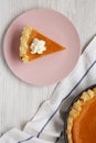 Homemade Thanksgiving pumpkin pie on a pink plate on a white wooden surface, top view. Top view, from above, flat lay Royalty Free Stock Photo