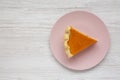 Homemade Thanksgiving pumpkin pie on a pink plate on a white wooden surface, top view. Overhead, from above, flat lay. Copy space Royalty Free Stock Photo