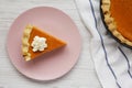 Homemade Thanksgiving pumpkin pie on a pink plate on a white wooden table, overhead view. Top view, from above, flat lay Royalty Free Stock Photo