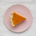 Homemade Thanksgiving pumpkin pie on a pink plate on a white wooden table, top view. Overhead, from above, flat lay. Close-up Royalty Free Stock Photo