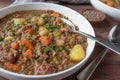 Lentil stew or soup with brown lentils, vegetables, potatoes and pork meat on a plate with spoon on wooden table. Royalty Free Stock Photo