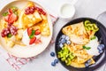 Homemade thin crepes served with curd cream, fruits and berries in black and white plates, top view Royalty Free Stock Photo