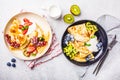 Homemade thin crepes served with curd cream, fruits and berries in black and white plates, top view Royalty Free Stock Photo