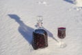 Homemade tincture of red cherry in a glass bottle and a wine crystal glass on a snow and white background Royalty Free Stock Photo