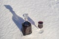 Homemade tincture of red cherry in a glass bottle and a wine crystal glass on a snow and white background Royalty Free Stock Photo