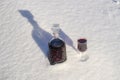 Homemade tincture of red cherry in a glass bottle and a wine crystal glass on a snow and white background Royalty Free Stock Photo