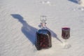 Homemade tincture of red cherry in a glass bottle and a wine crystal glass on a snow and white background Royalty Free Stock Photo