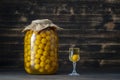 Homemade tincture of yellow cherry plum in glass jar and a wine crystal glass on wooden background, Ukraine, close up Royalty Free Stock Photo