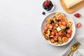 Homemade tiny pancakes with blueberry and strawberry on white table. View from above