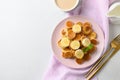 Homemade tiny pancakes with banana and strawberry on white table. View from above