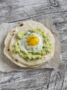 Homemade tortilla with mashed avocado and a fried quail egg.