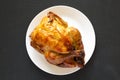 Homemade traditional rotisserie chicken on a white plate on a black background, top view. Flat lay, overhead, from above