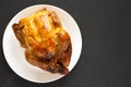 Homemade traditional rotisserie chicken on a white plate on a black background, top view. Flat lay, overhead, from above. Space