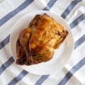 Homemade traditional rotisserie chicken on a white plate, overhead view. Flat lay, top view, from above