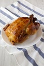 Homemade traditional rotisserie chicken on a white plate, side view