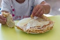 Homemade traditional Russian pancakes with condensed milk. Children`s hands and pancakes. The child is eating pancakes