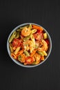 Homemade Tri-Color Penne Salad with Shrimp, Tomato and Basil Bread Crumbs in a Bowl on a black background, top view. Flat lay, Royalty Free Stock Photo