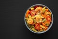 Homemade Tri-Color Penne Salad with Shrimp, Tomato and Basil Bread Crumbs in a Bowl on a black background, top view. Flat lay, Royalty Free Stock Photo