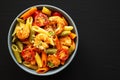 Homemade Tri-Color Penne Salad with Shrimp, Tomato and Basil Bread Crumbs in a Bowl on a black background, top view. Flat lay, Royalty Free Stock Photo