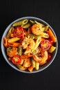 Homemade Tri-Color Penne Salad with Shrimp, Tomato and Basil Bread Crumbs in a Bowl on a black background, top view. Flat lay, Royalty Free Stock Photo