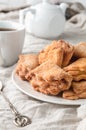 Homemade triangle cookies with curd filling sprinkled with sugar. On a white plate. Background gray linen. In the background is a