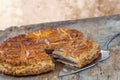 Epiphany Twelfth Night cake french galette des rois made of chocolate puff pastry, slice apart with the charm on wooden