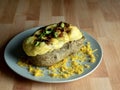 Homemade twice baked potato with cheddar cheese, green onions and bacon, baked to perfection and sitting on a gray plate