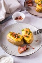 Homemade twice baked potatoes with cheese and bacon on a plate on the table. Vertical view