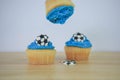Blue iced cup cakes with mini football decorations