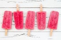 Homemade vegan raspberry coconut milk popsicles - ice pops - paletas with chia seeds on rustic white wooden background.