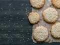 Homemade vegan tahini cookies are laid out on a dark table