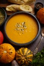 Homemade vegetarian pumpkin cream soup served in ceramic bowl. Decorated with seeds