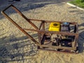 Homemade vibratory rammer device stands on the surface of a newly laid pavers on a sunny summer day. Concept of do-it-yourself