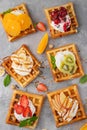 Homemade waffle with a cream, a variety of fruits, berries and sauces on a gray background. Traditional Belgian waffles. Top view Royalty Free Stock Photo