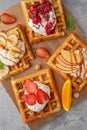 Homemade waffle with a cream, a variety of fruits, berries and sauces on a gray background. Traditional Belgian waffles. Top view Royalty Free Stock Photo