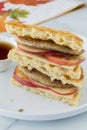 Homemade waffle and sausage sandwich halves in a stack.